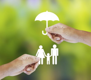 Hand holding a paper family and umbrella on green background
